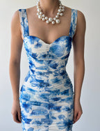 This image features the "Ocean Breeze Dress," a stylish and elegant garment with a strong, sea-inspired print. The dress displays a striking pattern in various shades of blue, reminiscent of ocean waves and sea life, contrasted against a white background.