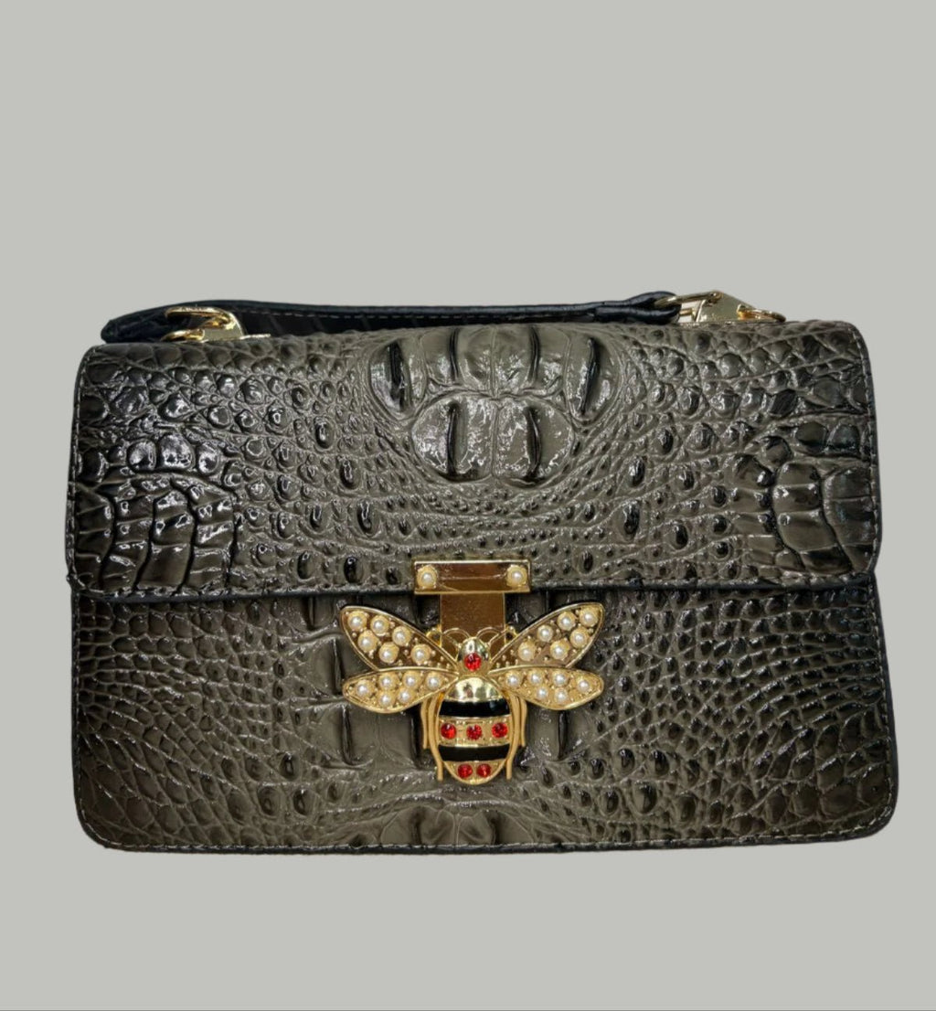 A medium-sized brown leather handbag with a textured surface and a decorative metal clasp featuring a bee design.