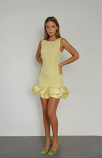 A woman wearing a sleeveless, pink mini dress with a ruffled hemline and matching pink boots.