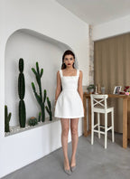 Woman in a white dress standing in a modern kitchen with cacti.