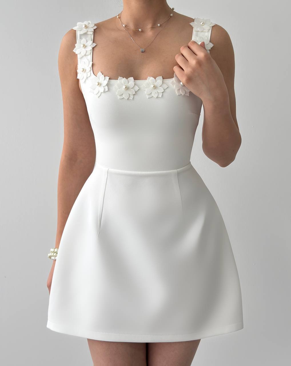 A white bridal dress with floral embellishments on the neckline and a flared skirt.