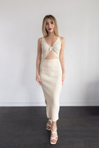 Woman wearing a cream-colored dress with a knot detail on a plain background