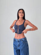 Woman wearing a denim corset top and high-waisted jeans against a plain background