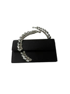 Black clutch with decorative chain handle on a white background