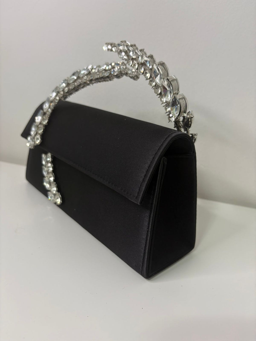 Black handbag with a decorative silver handle on a white background