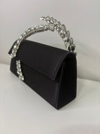 Black handbag with a decorative silver handle on a white background