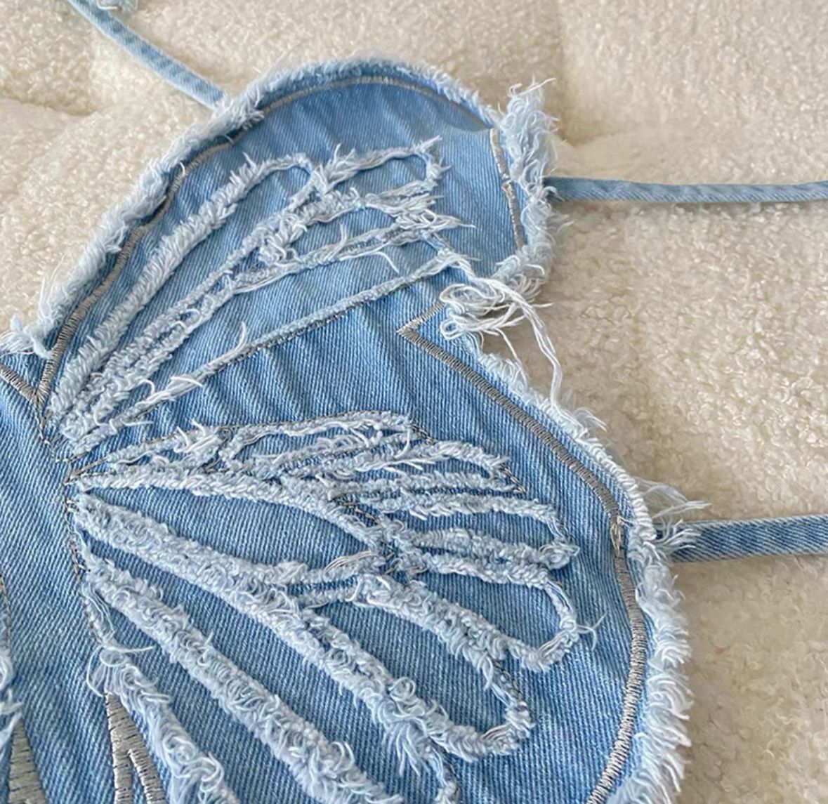 Denim top with lace detailing on a beige surface