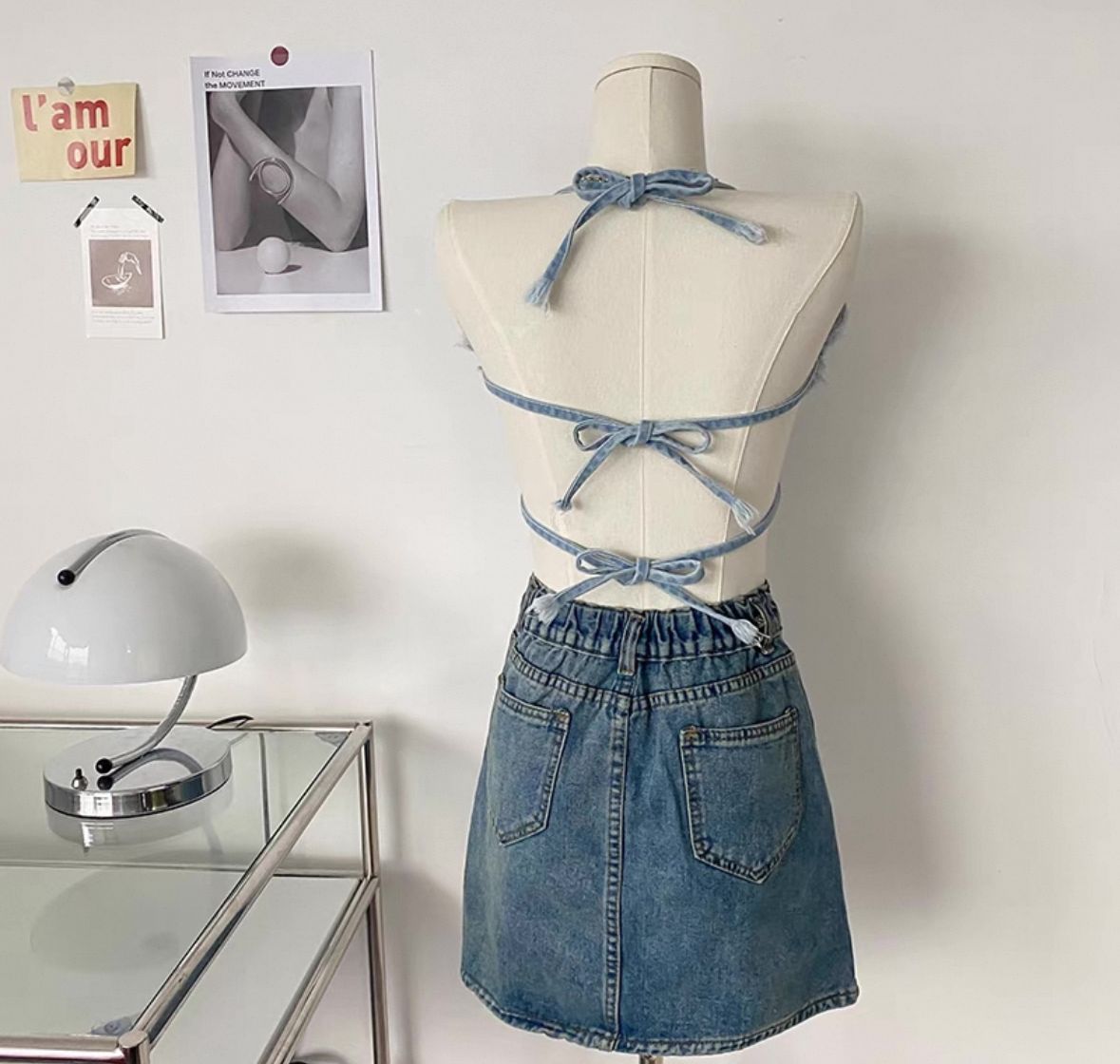 Mannequin wearing a denim outfit with a crop top and skirt on a plain background.