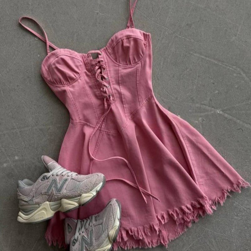 Pink dress with frayed hem and matching sneakers on a gray surface