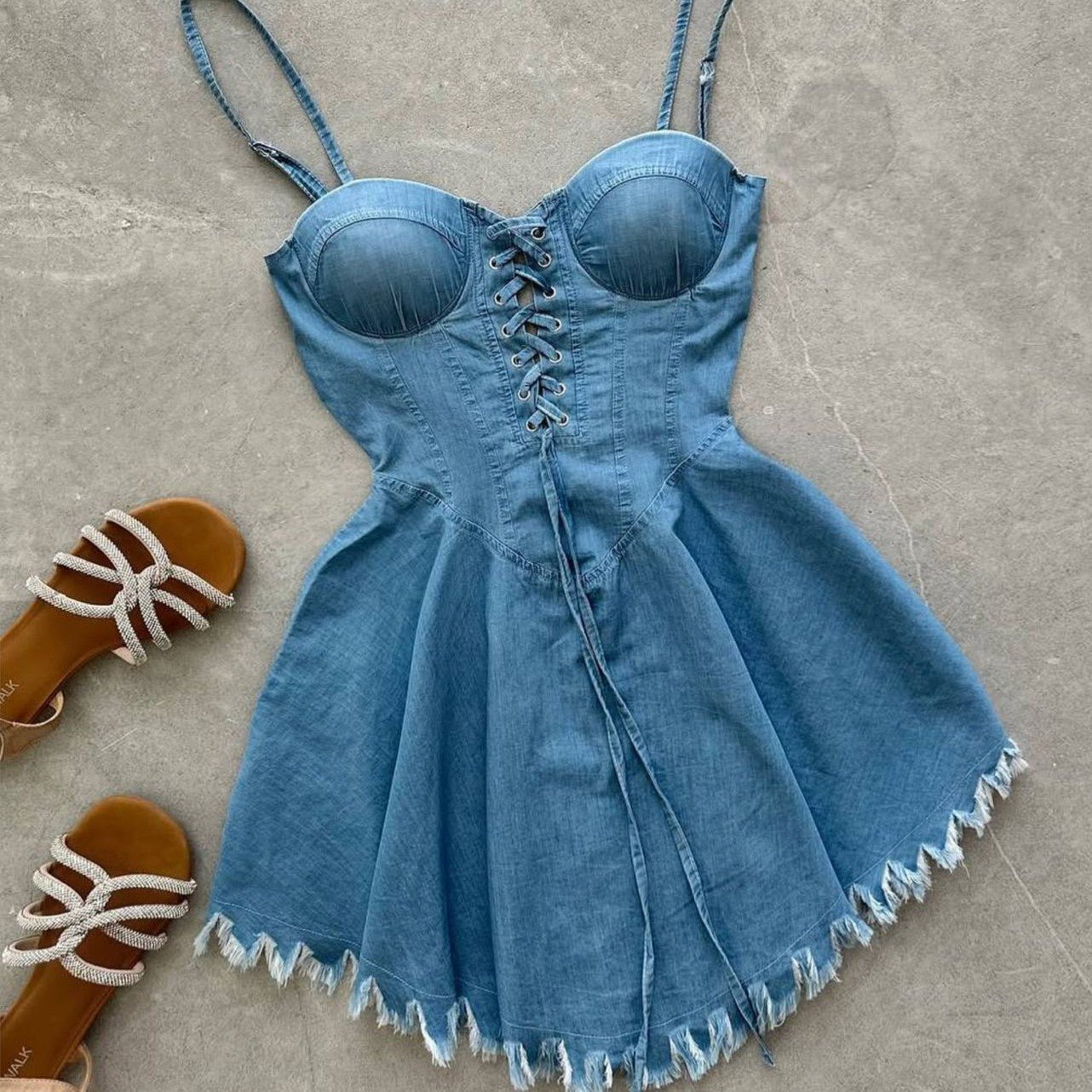 Blue denim dress with lace-up front on a gray surface