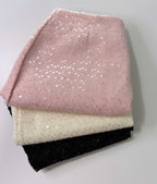 Collection of three skirts neatly stacked on top of each other, showcasing a variety of colors and textures. The top skirt is a soft pink with visible sequins sprinkled across its surface, giving it a subtle shimmer.