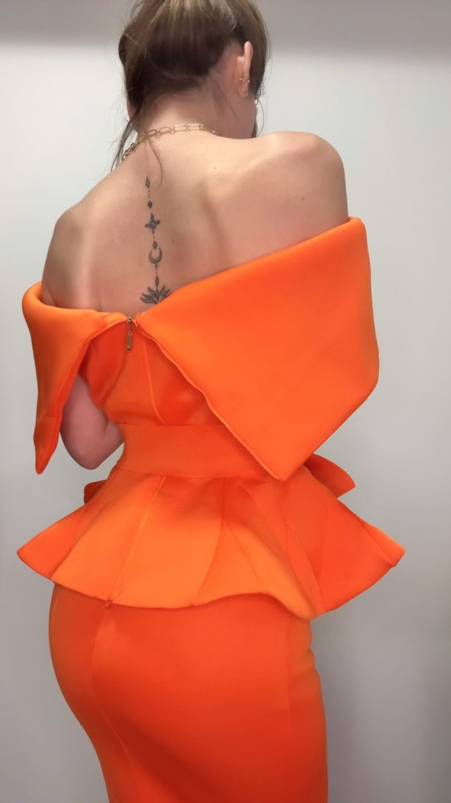Orange off-shoulder set with ruffled details on a plain background