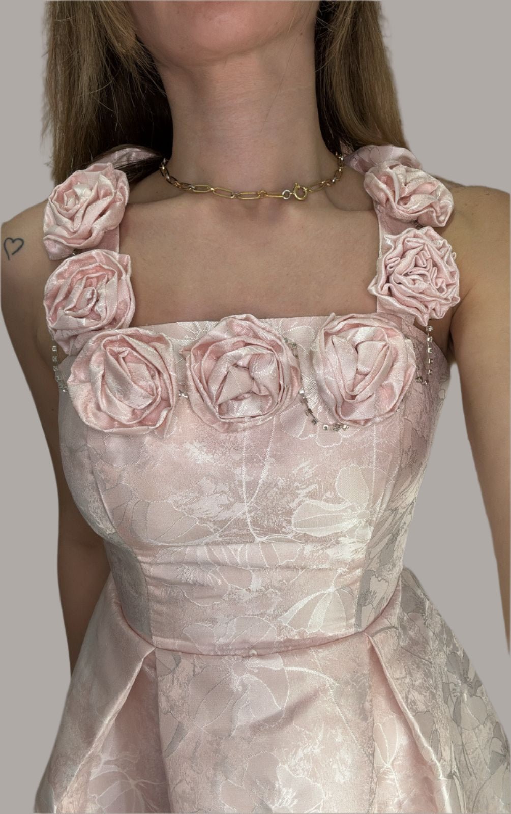 A close-up of a woman wearing a pink floral dress with a necklace.