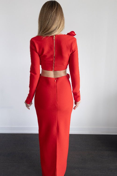 Woman wearing a red outfit standing against a white wall.