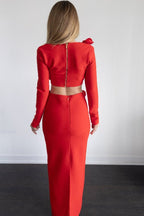 Woman wearing a red outfit standing against a white wall.