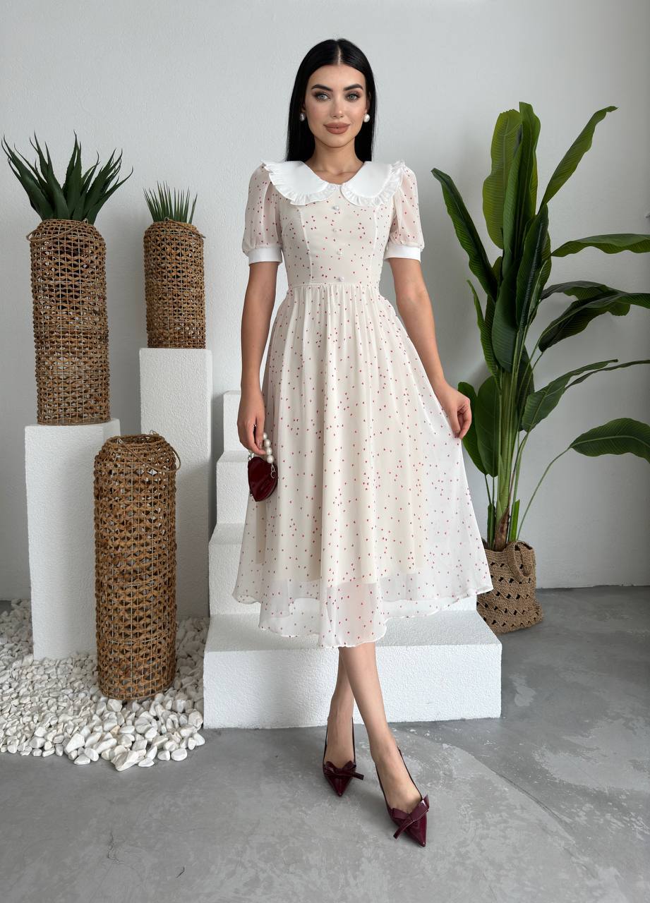 Woman in a white lace dress standing in a modern indoor setting with plants.