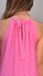 Close-up of a pink dress with a halter neck design on a plain background