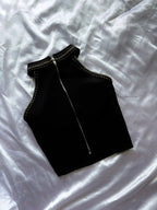 Black sleeveless top with a zipper on a white fabric background