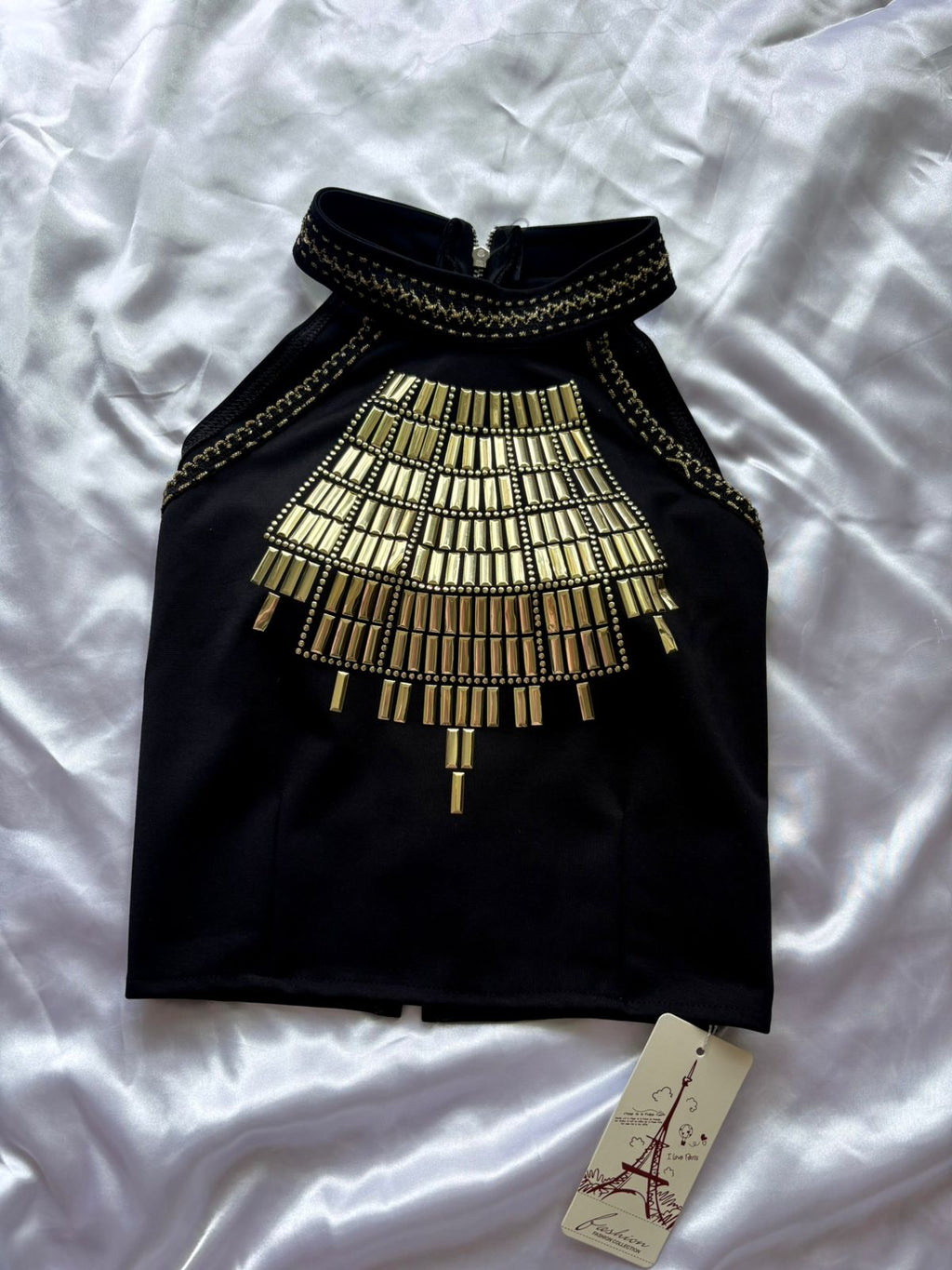 Black top with gold embellishments on a white background