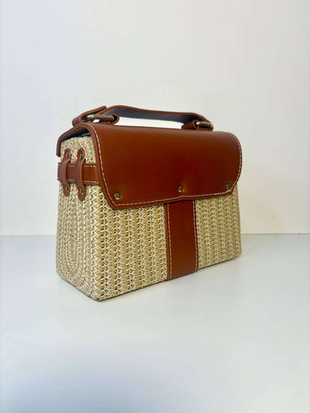 Woven handbag with brown leather accents on a white background