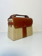 Woven handbag with brown leather accents on a white background