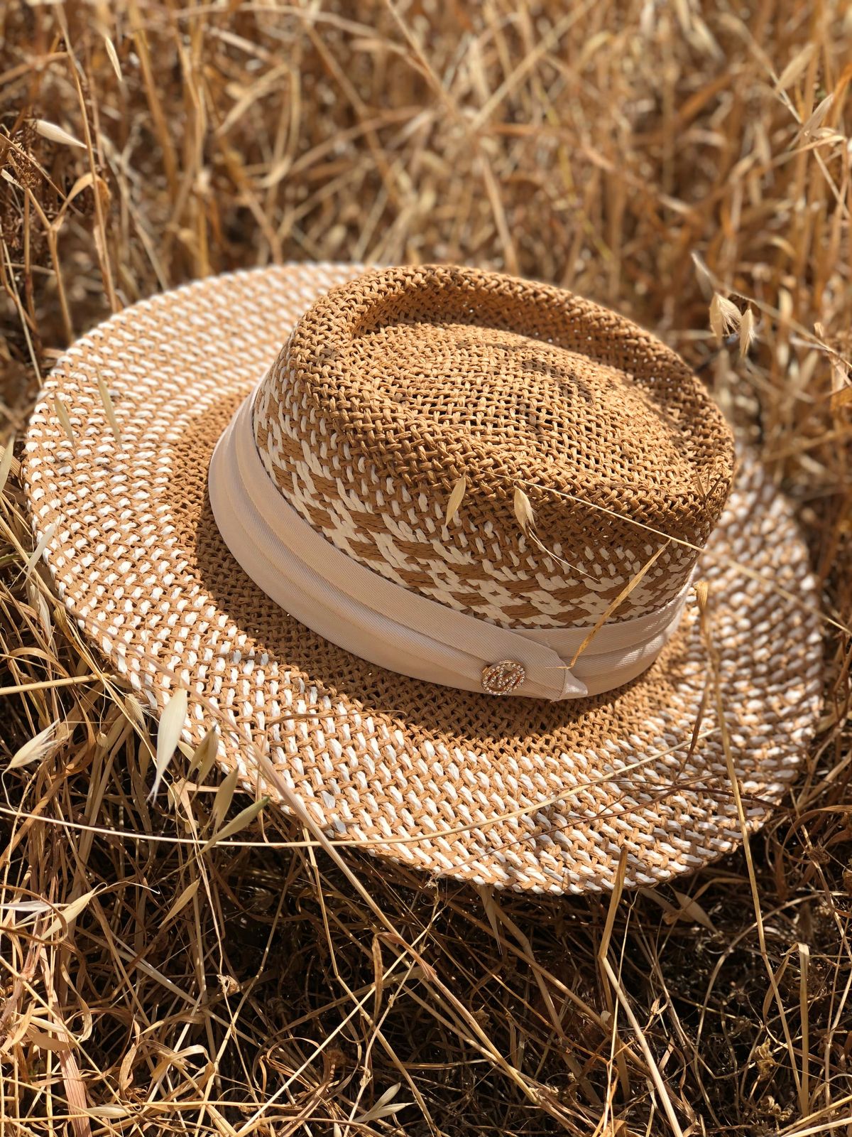 Woven straw hat with a white band on a bed of dry grass