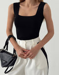 A woman wearing a black crop top and leggings, standing against a white background.