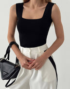 A woman wearing a black crop top and leggings, standing against a white background.