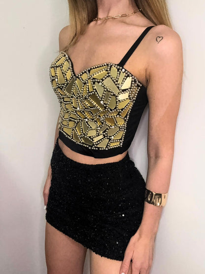 Woman wearing a black and gold crop top with a plain background