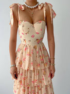 Floral dress with ruffled straps and a necklace on a plain background