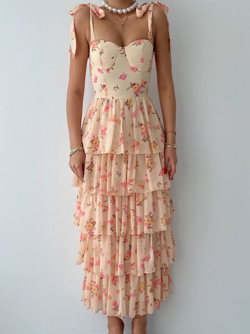 A floral print dress with ruffled layers and a sweet neckline, in a beige background.