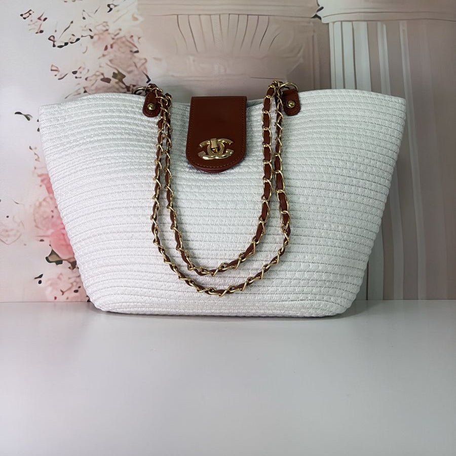 A white handbag with a beige tassel and brown leather details displayed against a floral background.