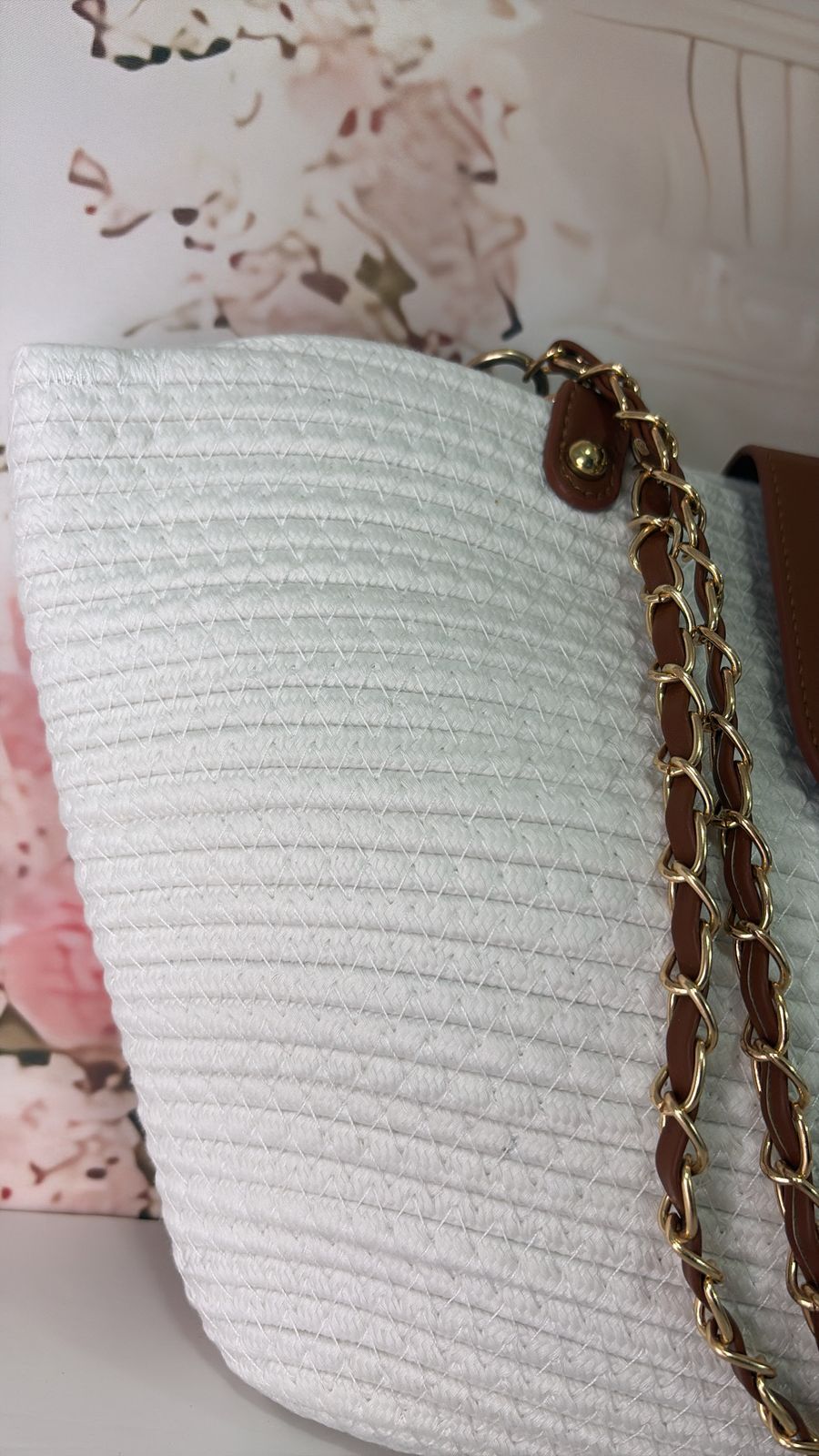 White textured bag with a gold chain on a floral background