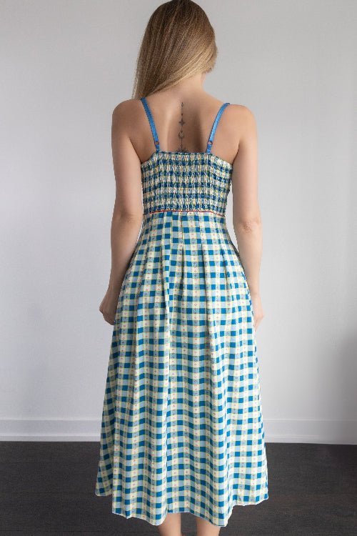 Woman wearing a blue and white checkered dress against a plain background