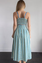 Woman wearing a blue and white checkered dress against a plain background