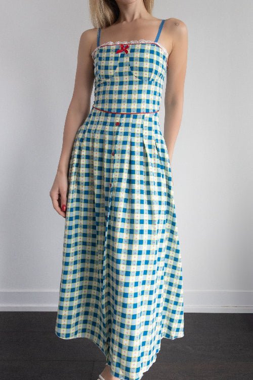 Woman wearing a blue and white checkered dress against a plain background