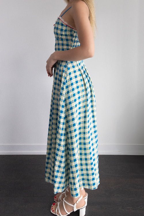 Woman wearing a blue and white checkered dress against a plain background