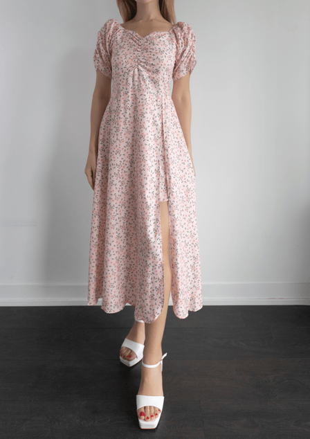 Woman wearing a floral dress with puff sleeves against a plain background