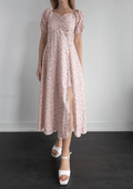 Woman wearing a floral dress with puff sleeves against a plain background