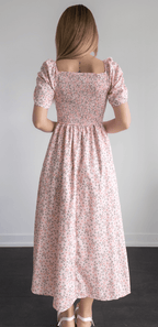 Woman wearing a pink floral dress against a plain background