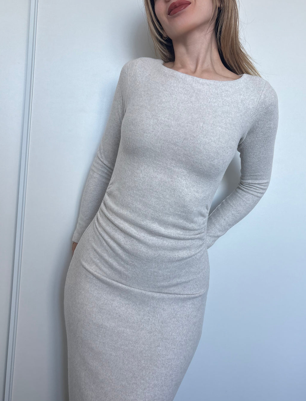 Woman wearing a fitted gray dress against a plain background