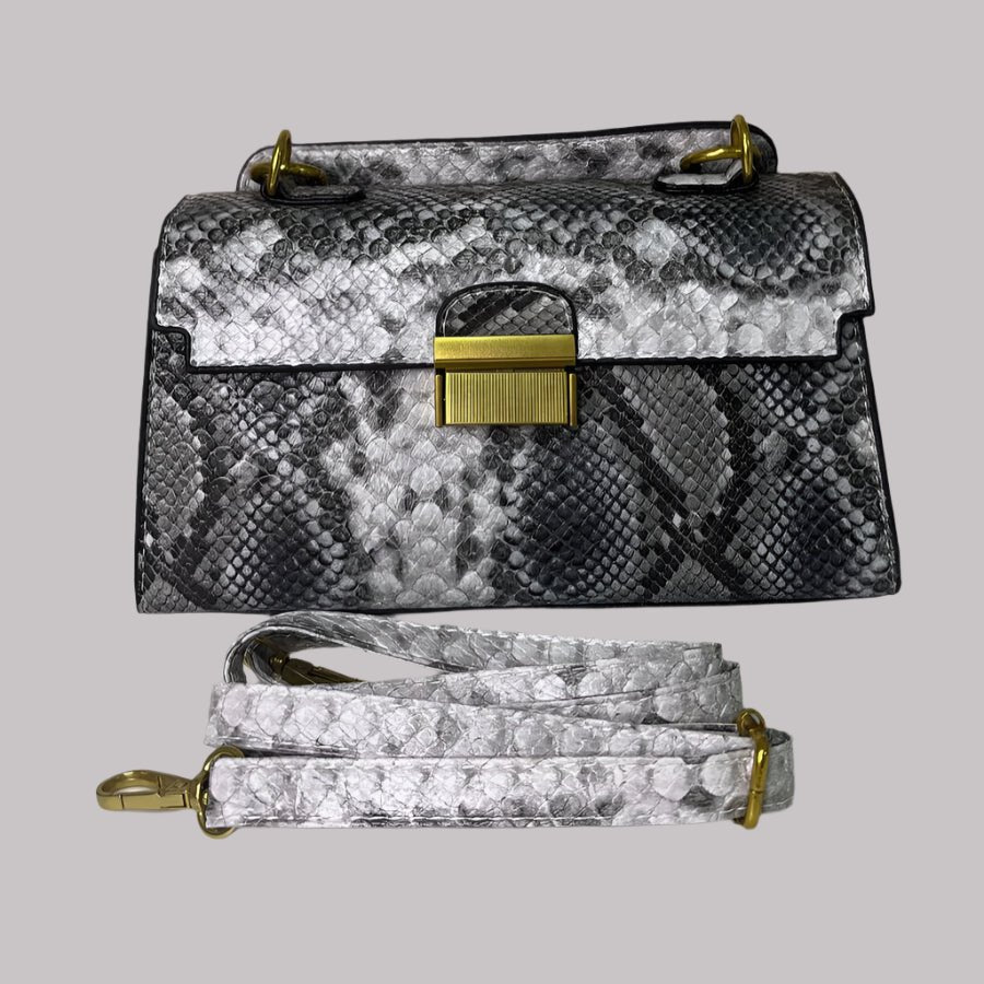 A snake print leather handbag with a shoulder strap, placed against a floral background.