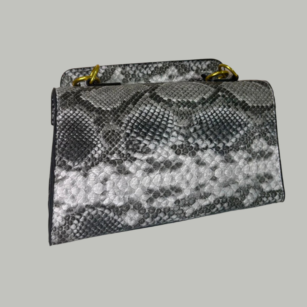 Snake print handbag on a white surface with floral decorations in the background.