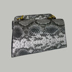 Snake print handbag on a white surface with floral decorations in the background.