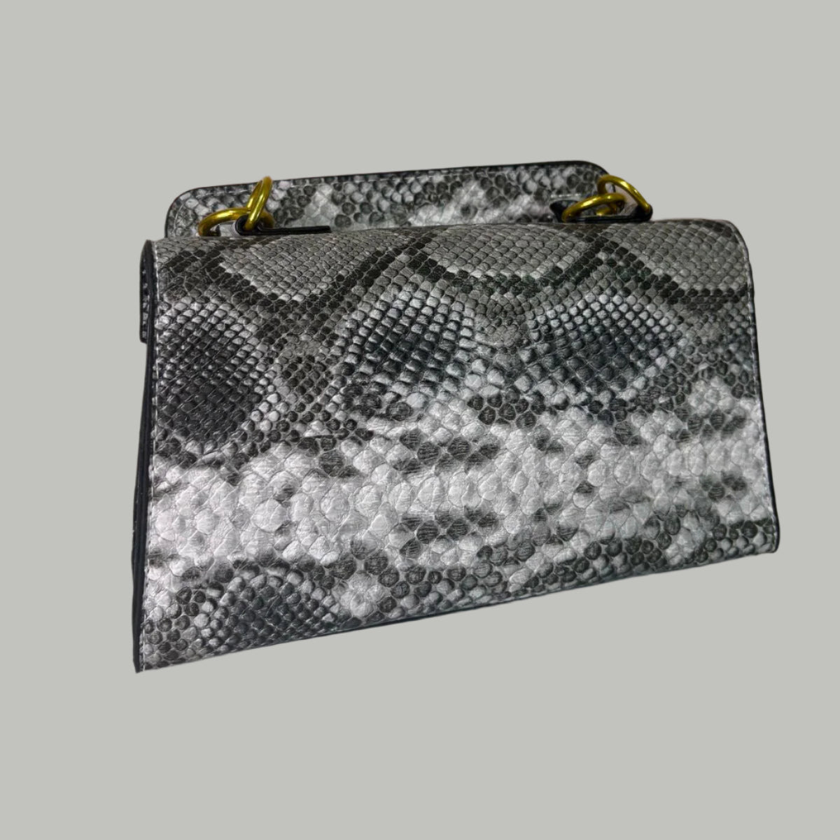 Snake print handbag on a white surface with floral decorations in the background.