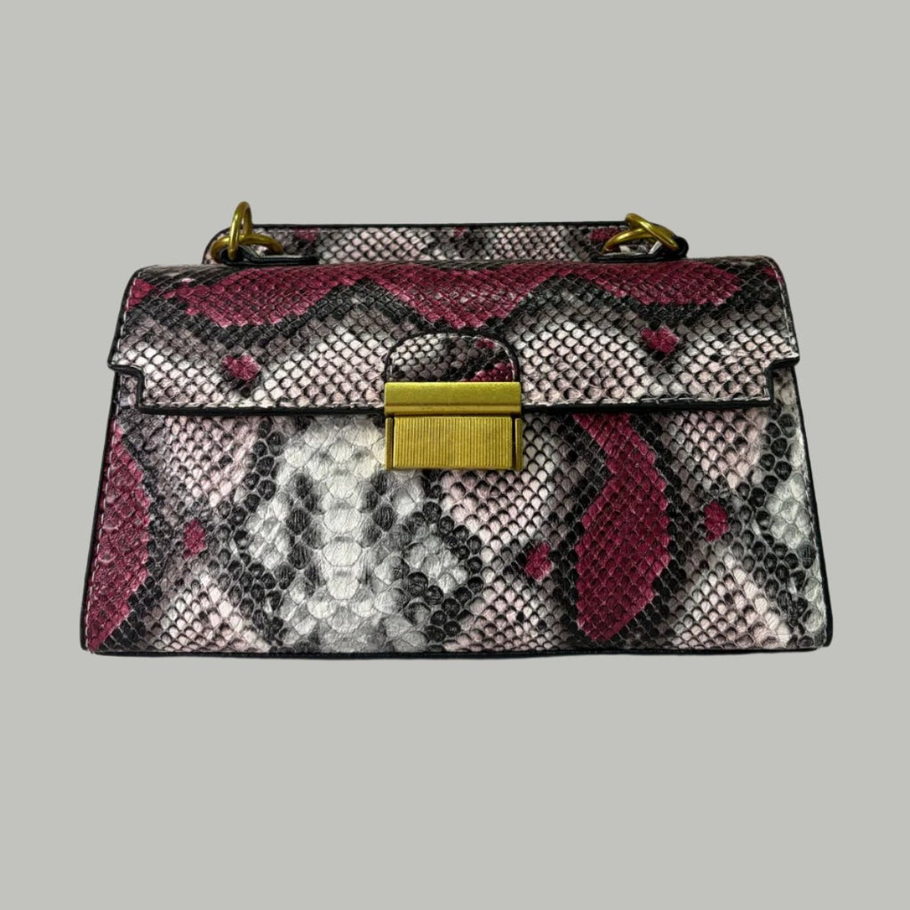 A snake print leather handbag with a shoulder strap, placed against a floral background.