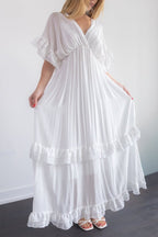 Woman wearing a white flowing dress against a plain background